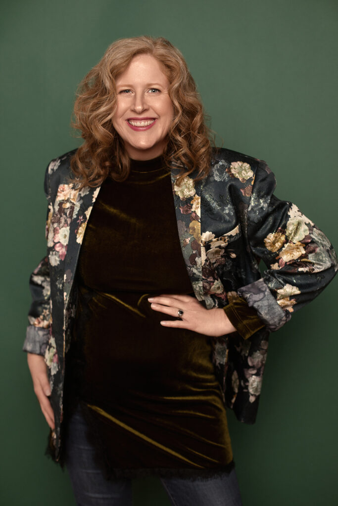 Jennifer in velvet top and floral blazer with warm smile and hand on hip.