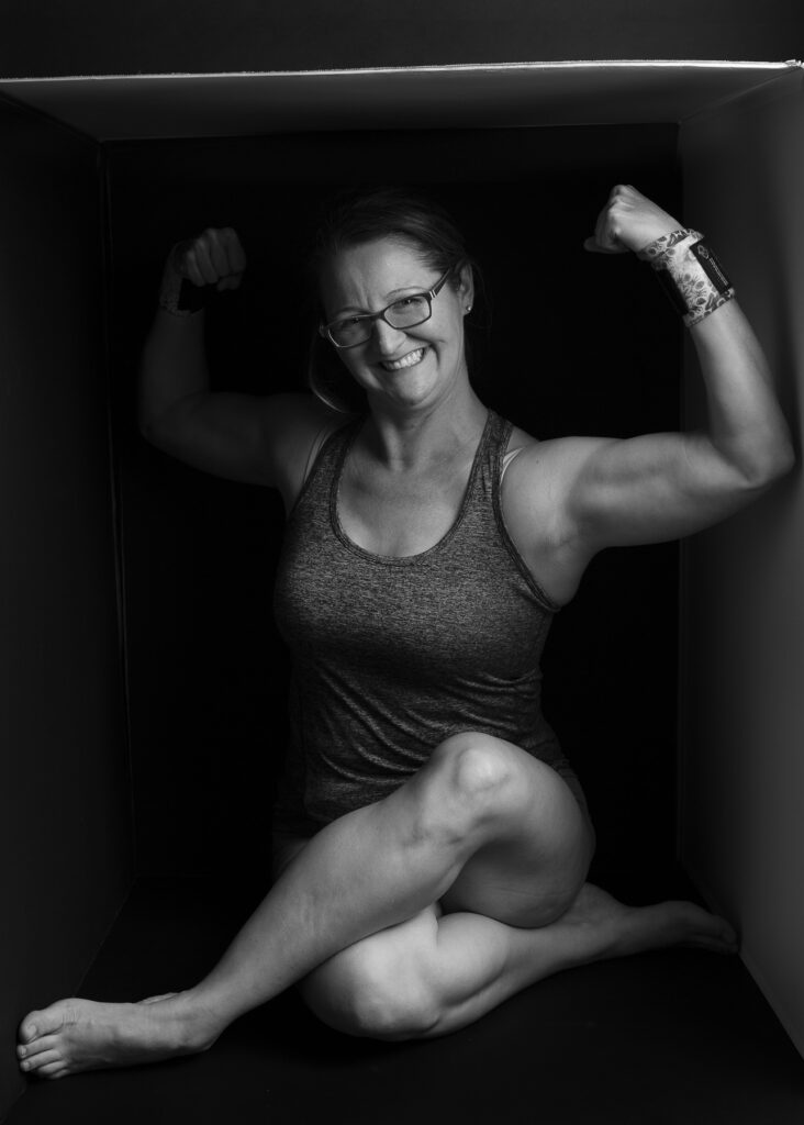 Dramatic black and white portrait of woman proudly displaying muscle tone by Redhead Creative Media in Chapel Hill, NC.