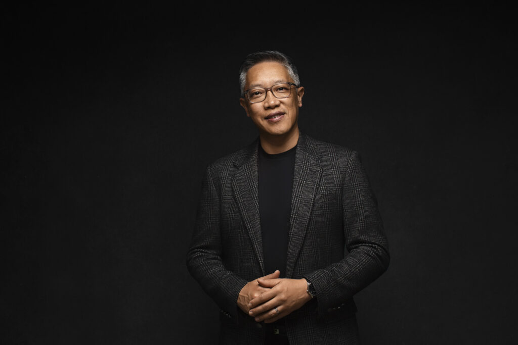 A man with a natural smile stands with hands held together during a Brand Authority Experience with Redhead Creative Media in Chapel Hill, NC.