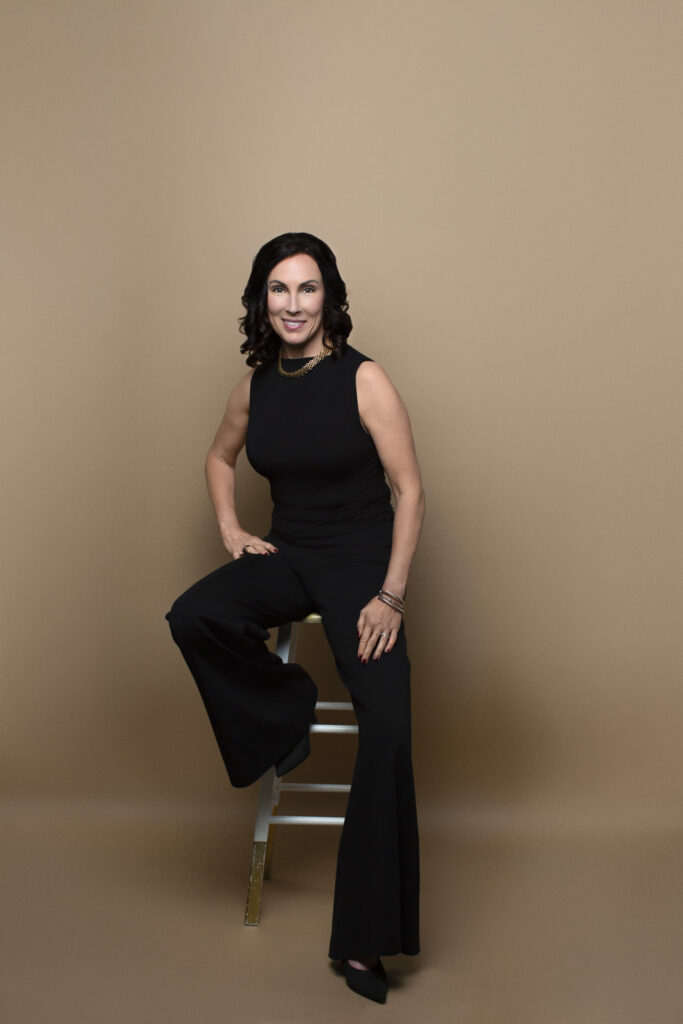 Woman in black seated on stool against warm neutral backdrop during a Brand Authority Experience portrait session at Redhead Creative Media, Chapel Hill, NC.