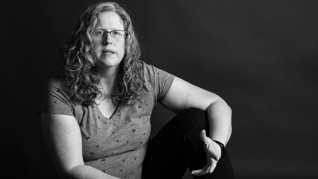 Black-and-white image of Jennifer talking while seated and open expression. Part of the Postpartum Project by Redhead Creative Media in Chapel Hill, NC.